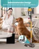 A woman and her dog are in a living room, with a cordless vacuum cleaner standing upright. Produktbild-Vorschau