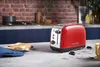 A red Russell Hobbs toaster sits on a kitchen counter next to some toast. Náhľad obrázku produktu