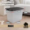 A large plastic storage box with a black lid is shown in a bedroom setting, with dimensions and weight indicated by text overlays. Produktbild-Vorschau