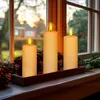Three LED candles on a wooden tray with pinecones and greenery, placed on a windowsill with a blurred outdoor background. Voir les images du produit