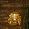 A hanging lamp with a rattan-like shade is illuminated against a brick wall. Anteprima dell’immagine prodotto
