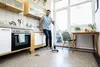 A man is cleaning the floor in a kitchen with a floor cleaner. Anteprima dell’immagine prodotto