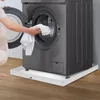 A person is loading laundry into a washing machine that is placed on a white tray. Náhled obrázku produktu