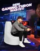A man is playing a video game while sitting on a white beanbag chair in a dimly lit room with gaming equipment. Produktbild-Vorschau