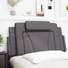A close-up view of a gray faux leather headboard with a white pillow in front of it, set against a white wall. Produktbild-Vorschau
