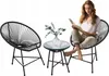 A woman is reading a book while sitting on a chair next to a small table with a vase of flowers. Náhled obrázku produktu