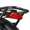 Close-up of a red bicycle tail light attached to a black rear rack. Produktbild-Vorschau