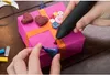 A person is using a black and pink glue gun to decorate a pink gift box with buttons and heart shapes. Produktbild-Vorschau