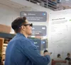 A man wearing AR glasses interacts with a holographic display showing a business report. Anteprima dell’immagine prodotto