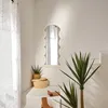 A corner of a room with a decorative mirror, plants, and shoes. Náhľad obrázku produktu
