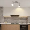 A modern kitchen with white cabinets, a marble backsplash, and wooden lower cabinets. A black range hood is mounted above the stovetop. Produktbild-Vorschau
