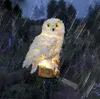 A decorative owl garden stake illuminated at night during a rain shower. Náhled obrázku produktu