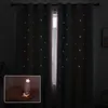A close-up of a hand holding a glowing star, with a background of star-patterned curtains. Náhled obrázku produktu