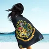 A person stands on a beach, wrapped in a blanket with the Hogwarts crest. Anteprima dell’immagine prodotto