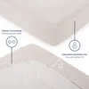Close-up of a fitted sheet showing its elastic band and a diagram illustrating its fit. Náhled obrázku produktu