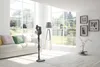 A modern living room with a sofa, vacuum cleaner, and large windows. Voir les images du produit