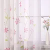 A sheer curtain with a floral pattern hanging in front of a window. Produktbild-Vorschau