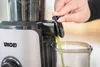 Eine Person öffnet den Ausguss des Unold Slow Juicer Sam und lässt frischen grünen Saft in einen dar Produktbild-Vorschau