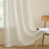 A close-up view of a sheer beige curtain hanging in front of a window, with a wooden chair and a book visible in the background. Produktbild-Vorschau