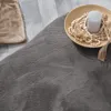 A close-up view of a fluffy gray rug with a beige rug and a decorative bowl with beads and a candle on it. Produktbild-Vorschau
