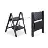 A product image showing a black two-step ladder in its open and folded states, side-by-side. Voir les images du produit