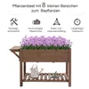 A wooden raised garden bed filled with purple flowers, shown with gardening tools and a watering can on a shelf below. Produktbild-Vorschau