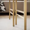 Close-up of the gold metal legs of a coffee table on a light wooden floor. Voir les images du produit