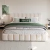 A beige upholstered bed with green and striped bedding in a bedroom setting. Produktbild-Vorschau