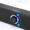 Close-up of a black soundbar with a glowing blue volume knob and control buttons. Voir les images du produit