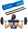 A woman is shown from behind, performing a squat with a barbell. A blue barbell pad is around the bar on her neck and shoulders. Náhled obrázku produktu