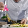 A chef is seasoning a dish with spices from a shaker. Produktbild-Vorschau