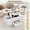 A white lift-top coffee table with storage compartments and a drawer, shown in a living room setting with a sofa and a side table. Podgląd zdjęcia produktu