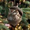 A Christmas ornament of an owl inside an acorn hanging on a decorated Christmas tree. Produktbild-Vorschau