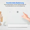 A close-up shot of a white mini dishwasher with a hand touching its control panel, set against a clean, bright background with some kitchen utensils and a cup in the foreground. Produktbild-Vorschau
