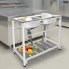 A commercial stainless steel double sink with a basket of vegetables on the shelf below, set in a commercial kitchen environment. Náhled obrázku produktu