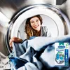 A woman is smiling and looking into a dryer drum filled with laundry. A product package is visible in the foreground. Anteprima dell’immagine prodotto