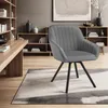 A gray upholstered armchair with black legs is placed on a rug in a room with bookshelves and a desk. Voir les images du produit