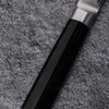 A close-up shot of a knife handle and part of the blade, resting on a textured gray surface. Náhled obrázku produktu