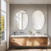 A modern bathroom vanity with two oval mirrors above it, illuminated by natural light from a large window. Podgląd zdjęcia produktu