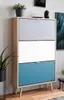 A tall, narrow shoe cabinet with three drawers of different colors (gray, white, and blue) is shown in a room setting. Produktbild-Vorschau