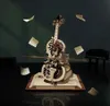 A mechanical cello model with floating sheet music and a miniature piano in the background. Voir les images du produit