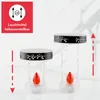 Two LED solar grave lights of different heights are displayed on a light gray and white marbled surface. The lights have black decorative bands and clear glass cylinders containing red LED flames. Red arrows and dashed lines indicate adjustable height. Produktbild-Vorschau