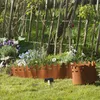A garden scene with a rustic wooden fence and flower beds, featuring metal garden edging. Produktbild-Vorschau