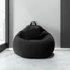 A dark gray bean bag chair sits on a light gray concrete floor against a light gray wall, with a dark gray wall section to the right and a window to the left. Voir les images du produit