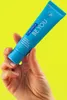 A hand holding a tube of toothpaste against a bright yellow background. Náhled obrázku produktu