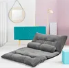 A gray floor sofa with two pillows is laid out in a room with a turquoise cabinet and a pink wall. Náhled obrázku produktu