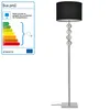 A floor lamp with a black shade and a silver stem decorated with spheres, next to an energy efficiency label. Produktbild-Vorschau