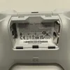 The back of a white Xbox wireless controller, showing the battery compartment and regulatory information. Produktbild-Vorschau