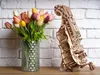 A wooden 3D puzzle model of a hurdy-gurdy sits next to a vase of tulips. Produktbild-Vorschau