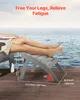 A person's legs are resting on a gray footstool placed on a wooden deck by the water. Produktbild-Vorschau